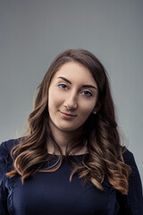 Fototapeta premium Young woman smiling with long brown hair on gray background