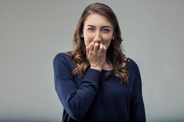 Young woman biting her nails, showing anxiety and insecurity