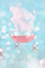 Pink cocktail in the glass, pink cloud and decorations, blurry lights in the light blue background. Pink party, anniversary, celebration, New Year' Eve, Valentines, birthday, anniversary, carnival. 