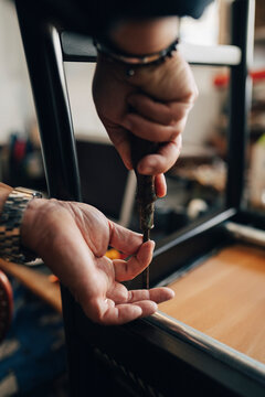 Hands of senior male owner repairing chair with tool while working at antique store