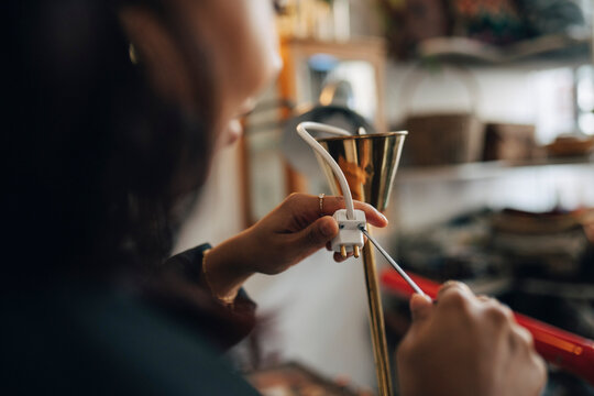 Female entrepreneur repairing electric socket at antique store