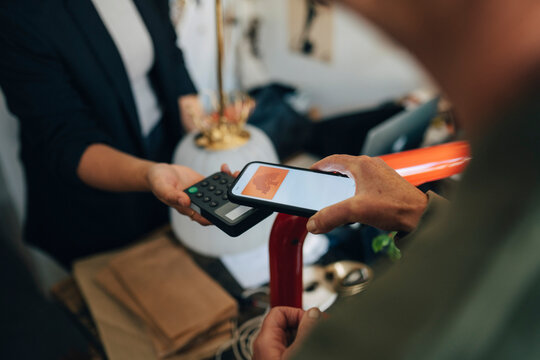 High angle view of customer making payment through smart phone at antique store