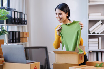 Asian women SME selling clothes online, She is answering customers' questions by laptop at home, Starting Small business entrepreneur freelance, Online business, SME concept.
