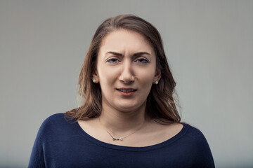 Young woman expressing disgust and skepticism on gray background