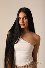 Fototapeta premium Vertical headshot of beautiful young woman with long dark hair looking at the camera. Mock-up.