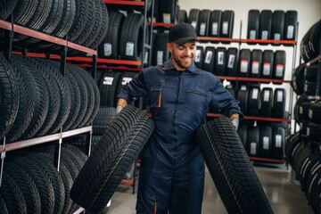 Walking and holding the tires. Man worker is maintenance station with wheels