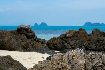 A rocky beach on Koh Samui, Thailand, featuring rugged volcanic rocks, soft sand, and a turquoise sea.