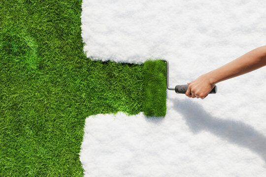 Hand painting green grass over white snow with paint roller, springtime renewal