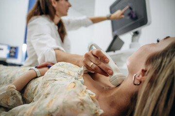 Side view. Woman is lying down and undergoing ultrasonic test of the thyroid gland