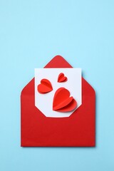 Paper card with red envelope and hearts on color background