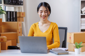 Happy young asian woman SME startup small business freelance work on parcel box and laptop computer , Online marketing packing box delivery SME e-commerce concept