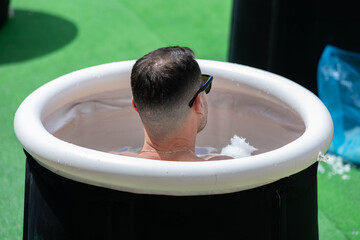 Boy immersing himself in little Circular Pool Filled with Water and Ice: Ice Baths and Wellness
