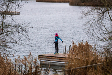 Woman stretching outdoors by a lake. Woman in active wear standing outdoors