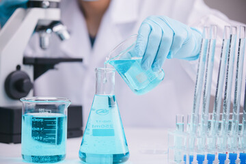 biochemical research scientist working with a microscope for the virus,Doctor man write a history of the experimental results in a , laboratory glassware containing chemical liquid for design.