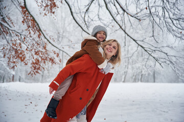 Sitting on a woman, flying. Mother and her daughter is on the winter meadow and forest