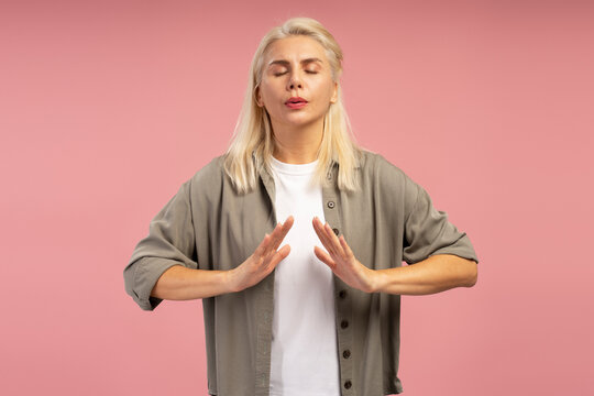 Blonde woman practicing breathing exercise on pink background