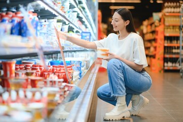 Young smiling happy woman 20s in casual clothes shopping at supermaket store with grocery cart