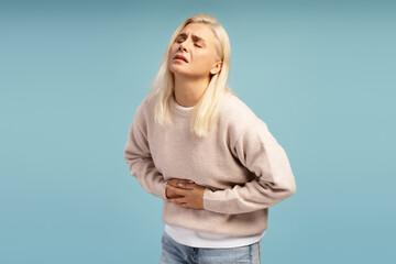 Woman suffering from strong stomach ache on blue background