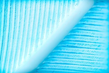 A macro photograph showcasing the intricate texture of a blue feather, revealing fine barbs and a central rachis