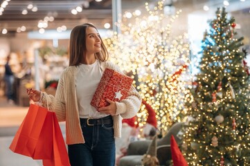 Garlands behind. New year shopping and presents. Woman is near the Christmas tree