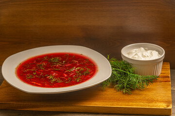 homemade vegetarian borscht, dill and sour cream on a wooden surface