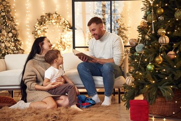 Man is reading story for boy. Happy family celebrating new year together at home