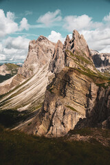 Fototapeta premium Massif montagneux imposant avec crêtes rocheuses et vallées verdoyantes sous un ciel nuageux