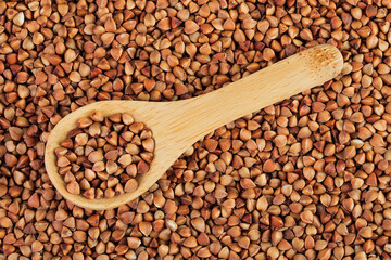 Raw buckwheat in wooden spoon as a background. Top view. Flat lay