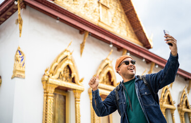 Asian traveling backpacker walking in temple at Bangkok Thailand Using smartphone to take photo and...