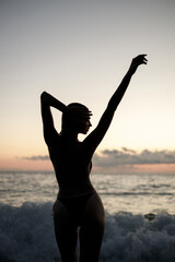 A beautiful silhouette of a woman enjoying the serene sunset at a peaceful beach
