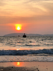 As the sun sets beautifully over the vast ocean, a distant boat floats