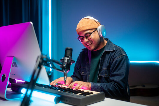 Professional Musician with condenser microphone and tablet for Mixing Mastering music. Music composer male composing a song with guitar and piano keyboard at digital Recording home studio