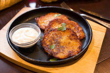 Potato pancakes with sour cream on frying pan