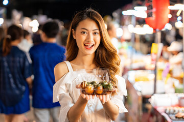 Asian woman enjoy eating noodles street food at night market. Traveler Asian blogger women Happy tourists Beautiful female with Traditional thailand bangkok food.