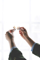 Close-up of business hands connecting with jigsaw puzzle achievements and goals Business concept, strategic planning as a team