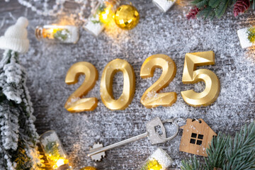 New Year 2025 golden numbers and House key with tiny form of home on festive grey wooden background...