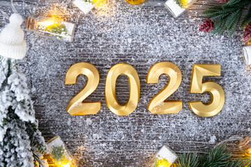Happy New Year golden numbers 2025 on cozy festive grey wooden background with Christmas tree,...