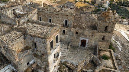 Fototapeta premium Aerial view of the church located in Craco, a ghost town in the province of Matera, Basilicata, Italy. The historic center was depopulated due to a landslide and has become a tourist destination.