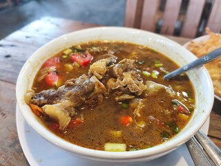 A bowl of steaming tongseng kambing, an Indonesian spicy goat soup.