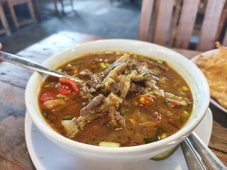 A bowl of steaming tongseng kambing, an Indonesian spicy goat soup.