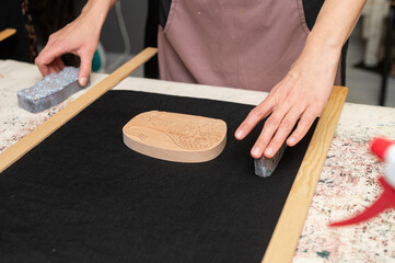 Female artisan setting up woodblock for printmaking on black fabric