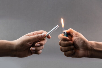 Male hands holding a cigarette and a lighter ready to light her fire - Harmful concept of Smoking.