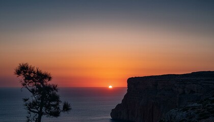 높은 절벽 위에 반짝이는 새벽녘의 태양, 어두운 하늘이 점차 물드는 장면
