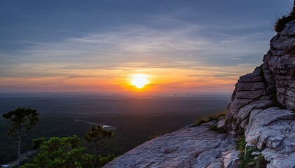 높은 절벽 위에 반짝이는 새벽녘의 태양, 어두운 하늘이 점차 물드는 장면