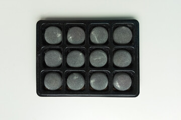 Gray mochi dessert in black packaging. White background. Top view.