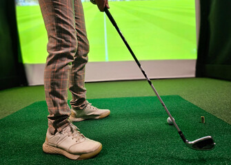 Golf player playing golf indoors on golf simulator closeup