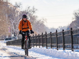 An exciting winter adventure in the city by bicycle. A man rides a bicycle on a snowy street