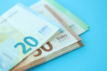Big amount of one hundred, twenty and fifty euro money bills on blue background