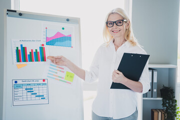 Photo of stats analyst blonde woman wearing formal white shirt and eyeglasses at office making presentation piecharts graphs