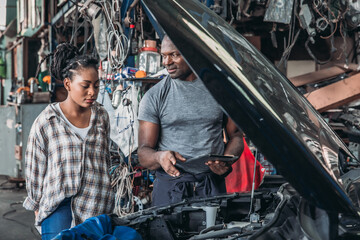 Mechanic Explains Car Repairs to a Woman in a Busy Workshop During the Day